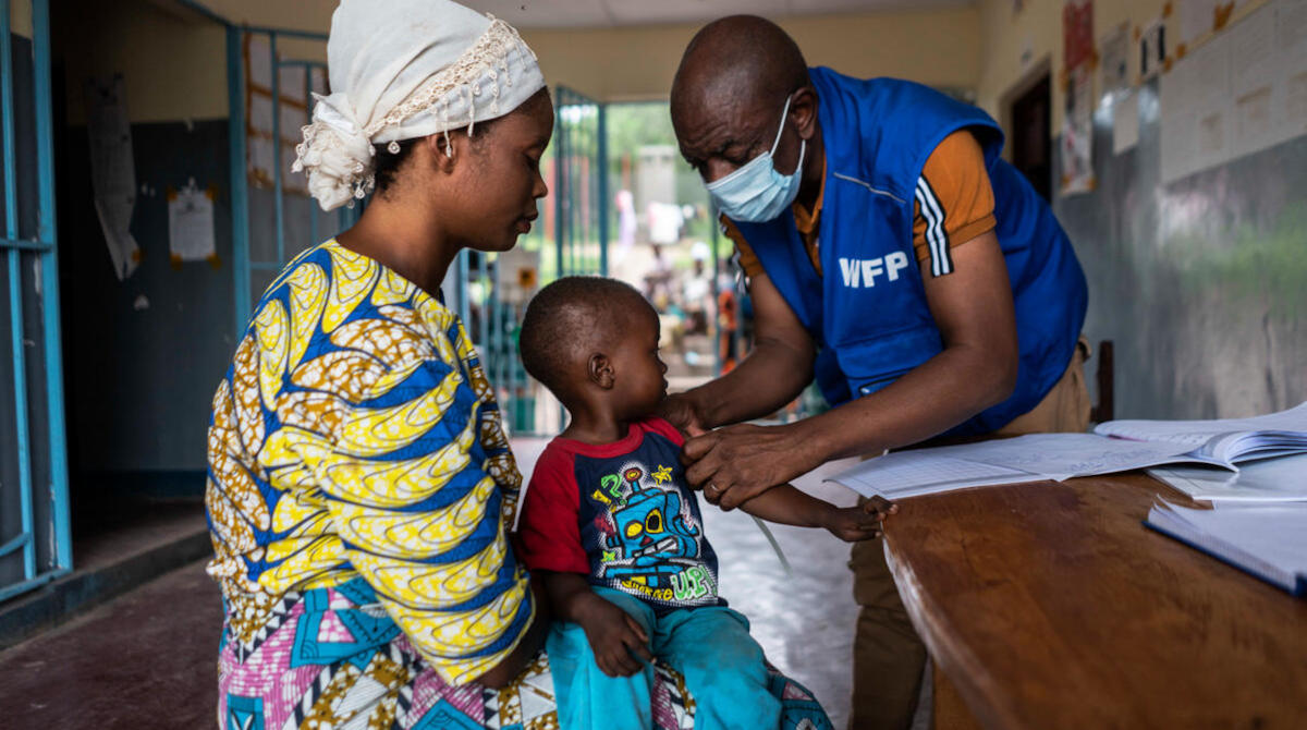 WFP staff, Francis Mpoyi, measures Maitre's arm during a routine check-up in Kalemie, Democratic Republic of Congo. Photo: WFP/Arete/Fredrik Lerneryd