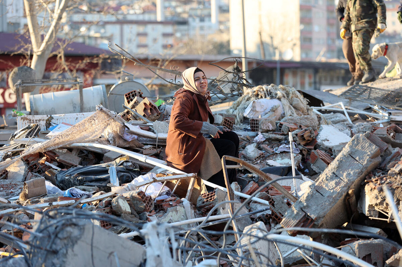 eine Frau sitzt auf den Trümmern eines zerstörten Gebäudes in Kahramanmaras