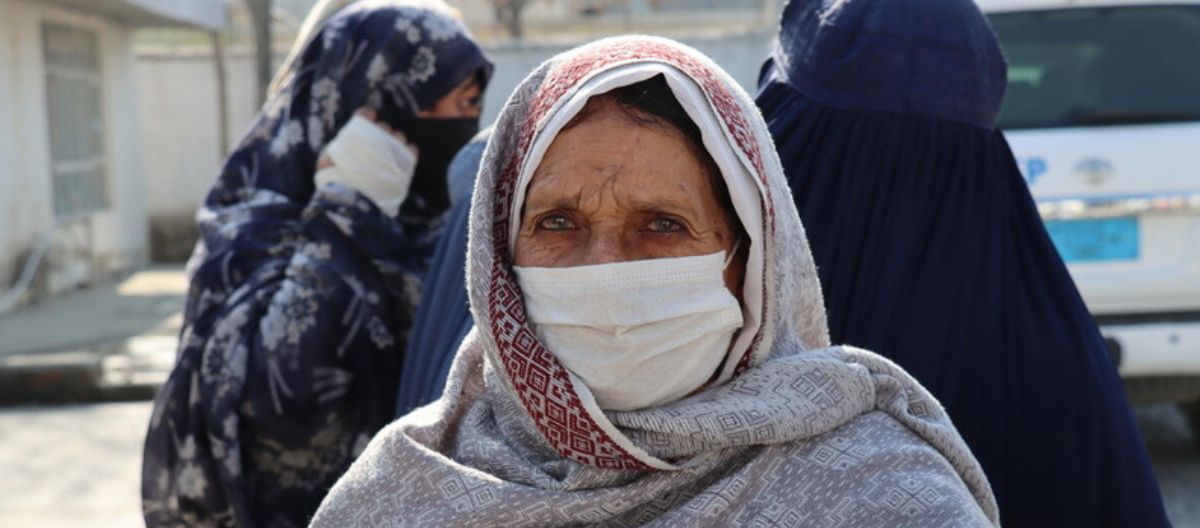 Auf diesem Bild sieht eine afghanische Frau mit medizinischer Maske direkt in die Kamera.