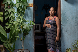 In Sri Lanka, 26-year-old Keshala stands in her doorway holding her pregnant belly. National programmes for pregnant and lactating women are seriously constrained by the economic crisis.
