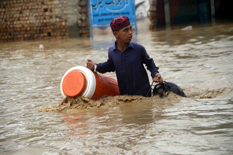 Auf diesem Foto watet ein kleiner Junge am 27. August 2022 durch ein überschwemmtes Gebiet in Peshawar, Khyber Pakhtunkhwa, Pakistan. 