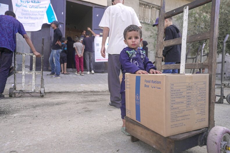 Ein kleiner Junge neben einem WFP-Lebensmittelpaket. © WFP/Jaber Badwan