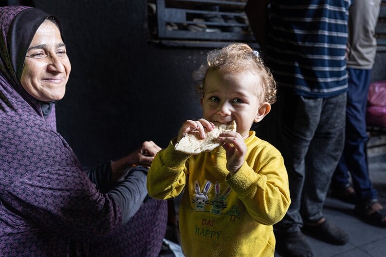 Ein kleines Mädchen mit seiner Mutter in Gaza, welches Brot isst. WFP/Nour Hammad