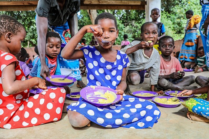 Eine Gruppe von Kindern isst eine warme Mahlzeit, die im Rahmen eines der WFP-Schulmahlzeitenprogramme in Malawi bereitgestellt wurde.  © WFP/Simon Pierre Diouf