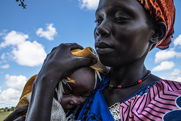 A woman in South Sudan shields her child from the sun