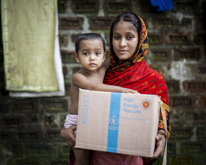 Zakia und ihre zweijährige Tochter Shimu im Büro des Bezirksbeauftragten in Masimpur, um mit Mikronährstoffen angereicherte Kekse abzuholen. © WFP/Sayed Asif Mahmud