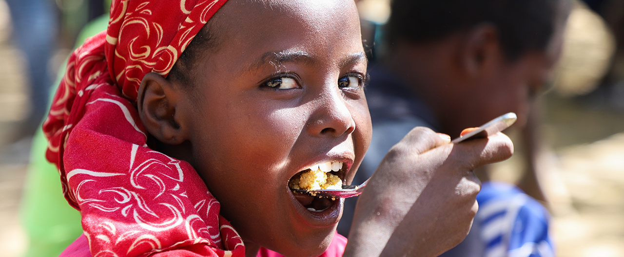 Ein Kind welches in die Kamera sieht und isst.
