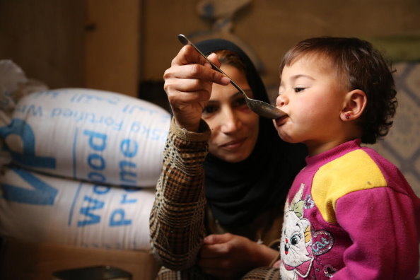 Foto: WFP/Abeer Etefa, Eine Frau, die mit ihrer Familie aus Douma im ländlichen Damaskus nach Adra vertrieben wurde ernährt ihre 18 Monate alte Tochter.