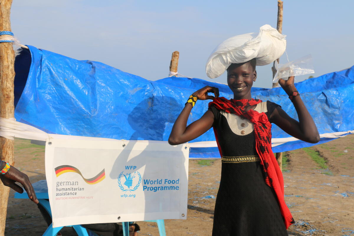 Eine Frau mit Nahrungsmittelrationen, die per Luftabwurf in Garryiel, im Südsudan, eingetroffen sind.