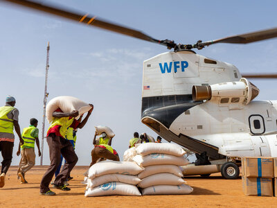 Mitarbeiter laden Säcke mit Bargeldtransfers und Nahrungsmitteln aus einem Schwerlast-Hubschrauber des WFP aus