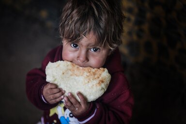 Abboud isst ein frisch gebackenes Brot, das seine Mutter in ihrem Lehmofen mit dem Weizenmehl gebacken hat, das sie von WFP erhält