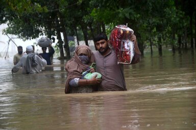 Hussain Ali / Anadolu Agency Vertriebene waten durch ein überschwemmtes Gebiet in Peshawar, Khyber Pakhtunkhwa. Seit Juni sind in Pakistan fast 900 Menschen durch schwere Monsunregenfälle und Überschwemmungen ums Leben gekommen, Tausende wurden vertrieben und Millionen weitere sind betroffen.