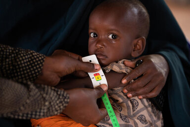© WFP/Samantha Reinders Auf diesem Foto wird Mashallah (2) von seiner Mutter Dahera (28) im Arm gehalten, während sein MUAC gemessen und auf Unterernährung untersucht wird.