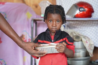 Ein Mädchen erhält eine warme Mahlzeit in einer Einrichtung für Binnenflüchtlinge in der Gemeinde Port-au-Prince.