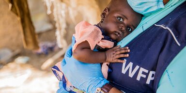 WFP-Mitarbeiter mit Hassana, einem 10 Monate alten Kind, das sich nach einer WFP-Intervention von der Unterernährung erholt hat.