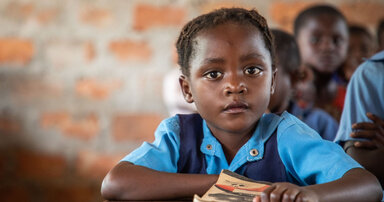 © WFP/Vincent Tremeau Ein kleines Kind in Schuluniform in der Schule, welches in die Kamera blickt