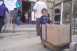 WFP/ Jaber Badwan Ein Kind steht neben dem Lebensmittelpaket, das sein Vater gerade an einer WFP-Ausgabestelle abgeholt hat
