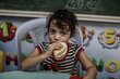 Ein junges Mädchen isst Brot, das vom Welternährungsprogramm (WFP) in einer UNRWA-Schule verteilt wurde, die in Notzeiten als Schutzraum dient.