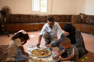 A Palestinian family sits on the floor around a bowl, eating a traditional shared meal. Photo: WFP/Hugh Rutherford