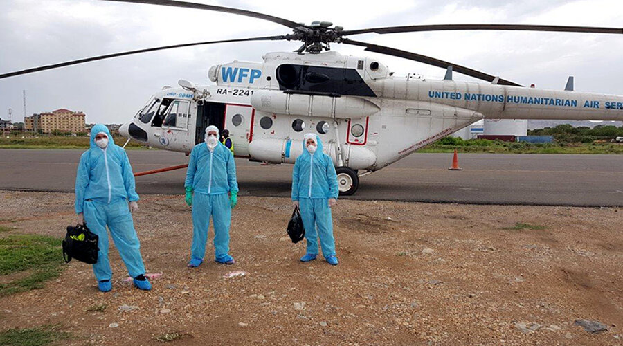 Health workers in protective suits are pictured outside a helicopter