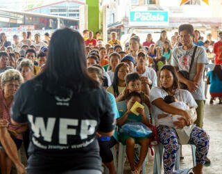 WFP-Mitarbeiter*innen erklären den Mitgliedern der Irosin-Gemeinschaft, die am WFP-Projekt für vorausschauende Hilfe teilnehmen, das Registrierungsverfahren. Foto: WFP Philippinen/Arete