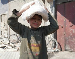 Syrien, Aleppo. Kinder stellen sich mit ihren Eltern in die Schlange oder werden allein zum Brot holen geschickt, bevor sie zur Schule gehen. Foto: WFP/Hussam Al Saleh