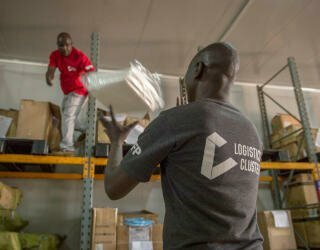 WFP-Logistiker*innen überprüfen die persönliche Schutzausrüstung (PSA), die im temperaturgeführten Lager in Lologo, Juba, ausgeladen wird. Foto: WFP/Giulio d'Adamo