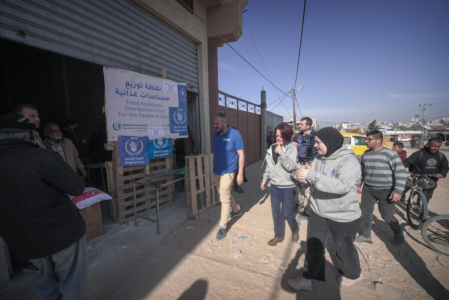 Two women lead a small group of men to the entrance of a WFP warehouse