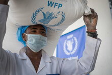 Photo: WFP/Mohammed Sami, humanitarian workers are carrying the food bags from the store into the truck. 