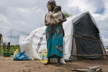 WFP/Grant Lee Neuenburg, Eine Frau und ihr Baby stehen vor einem Zelt in einem Flüchtlingscamp, Cabo Delgado, Mosambik.