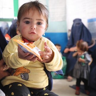 Kind mit nährstoffreichem Snack, der von WFP verteilt wurde, um die Unterernährung bei Kindern zu verringern