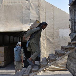 WFP-Mitarbeiter tragen Kisten mit angereicherten Nahrungsmitteln, die in Afghanistan verteilt werden sollen.