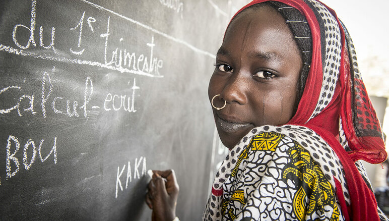 Kaka Marabou schreibt ihren Namen an die Schultafel in Yakoua, Tschadsee. Flüchtlinge, Vertriebene und andere arme Gemeinschaften im Tschadseebecken sind auf humanitäre Hilfe angewiesen, um zu überleben, und auch der Zugang zu grundlegender Bildung ist begrenzt. WFP/Giulio d'Adamo